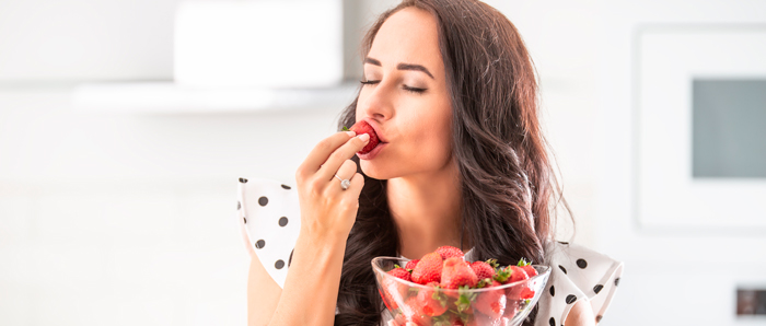 Mujer morena comiendo fresas y controlando la ansiedad de comer